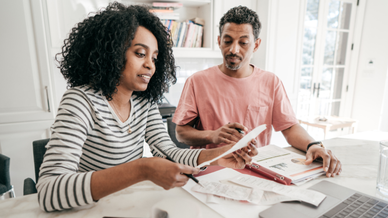 Black couple sitting at a table reviewing their finances together.